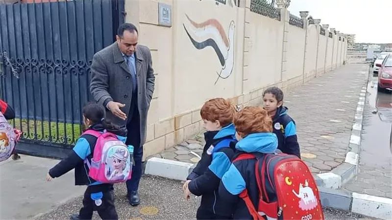 مدير المدرسة يستقبل التلاميذ أمام البوابة تحت الأمطار