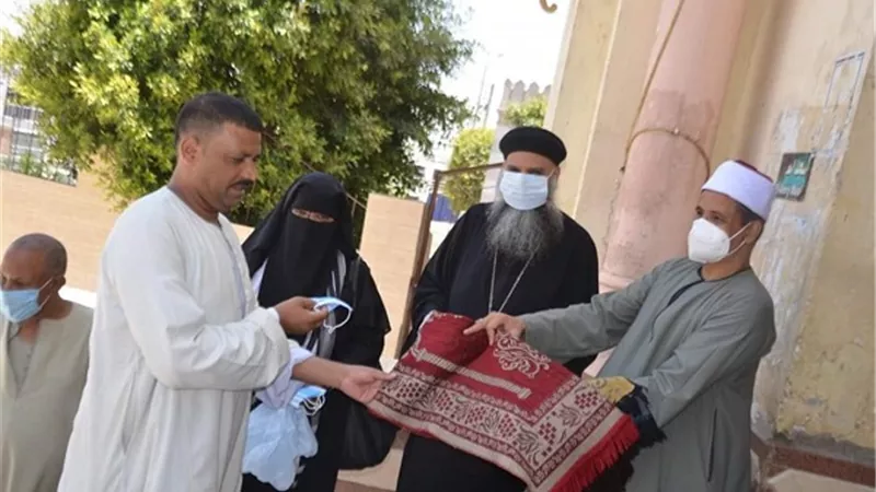 وكيل مطرانية إسنا يوزع كمامات ومصليات أمام مسجد العتيق