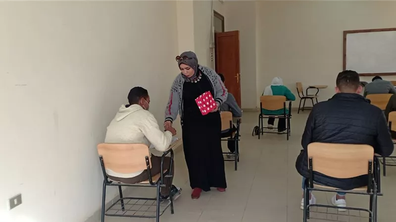 استاذه جامعيه تقوم بتوزيع الشيكولاته على الطلاب اثناء الامتحانات بقنا