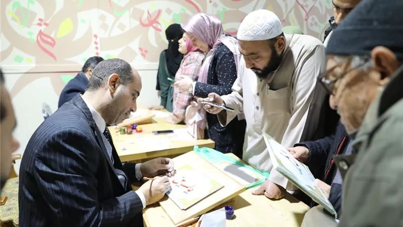 ركن الخط العربي يد تكتب والأخرى ترسم البسمة لزوار جناح الأزهر